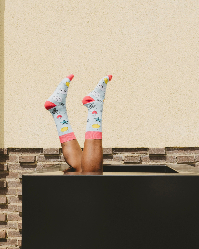 A pair of legs with socks on coming out of a black box.